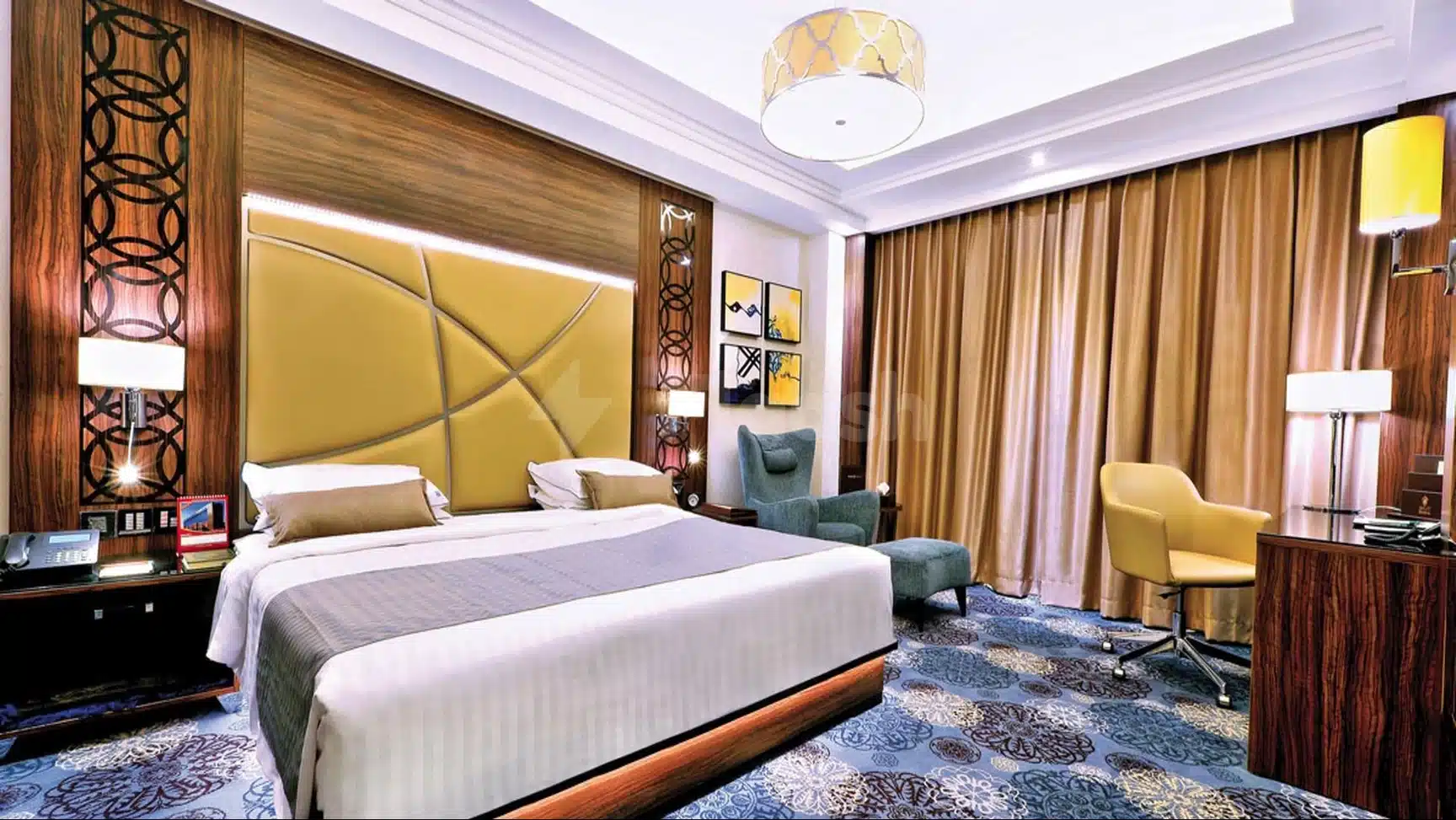 Luxury guest room at Casablanca Grand Hotel, Jeddah, featuring a mustard-yellow upholstered headboard and patterned blue carpet