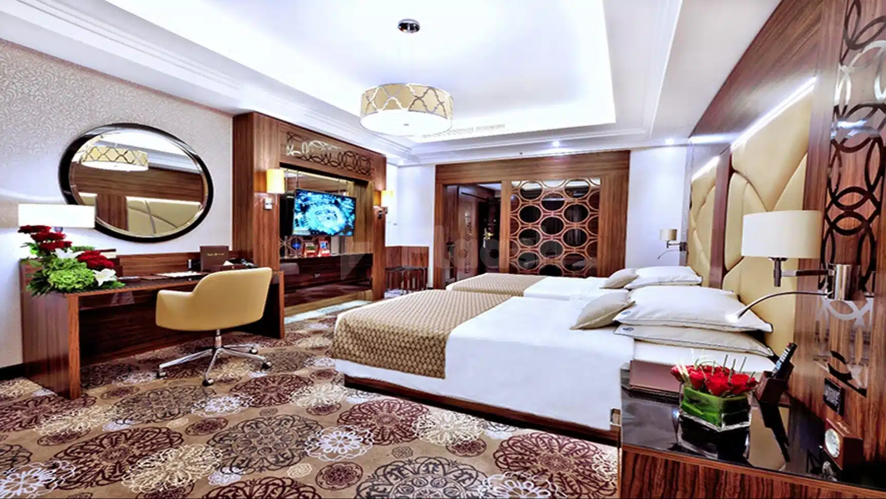 Luxury guest room at Casablanca Grand Hotel, Jeddah, featuring twin beds with floral carpeting and a round mirror