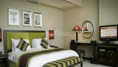 Guest room at Elaf Jeddah Hotel, Jeddah, featuring a green upholstered bedhead and framed wall art above it