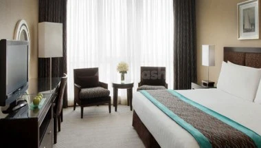 Guest room at Elaf Jeddah Hotel, Jeddah, featuring a king-sized bed with turquoise accent runner and armchairs by
