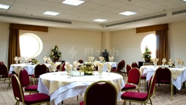 Banquet hall at Makarim Al-Bait Hotel, Mecca, featuring round tables with white linens and red chairs under recessed