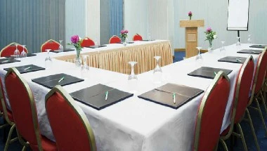 Conference room setup at Gloria Inn Najran, Najran, with red chairs arranged around a long table covered