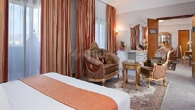 Guest room at Gloria Inn Najran, Najran, featuring patterned curtains and a vintage-style armchair near a mirrored vanity