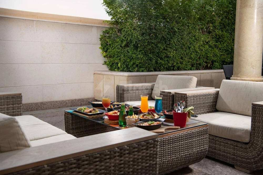 Outdoor lounge at Park Inn by Radisson, Makkah Al Naseem, Mecca, with wicker furniture and lush greenery backdrop