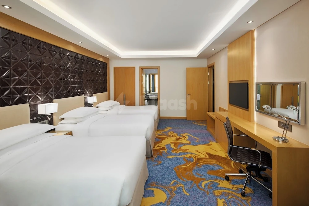 Guest room at Sheraton Makkah Jabal Al Kaaba Hotel, Makkah, with textured headboard wall and patterned carpeting
