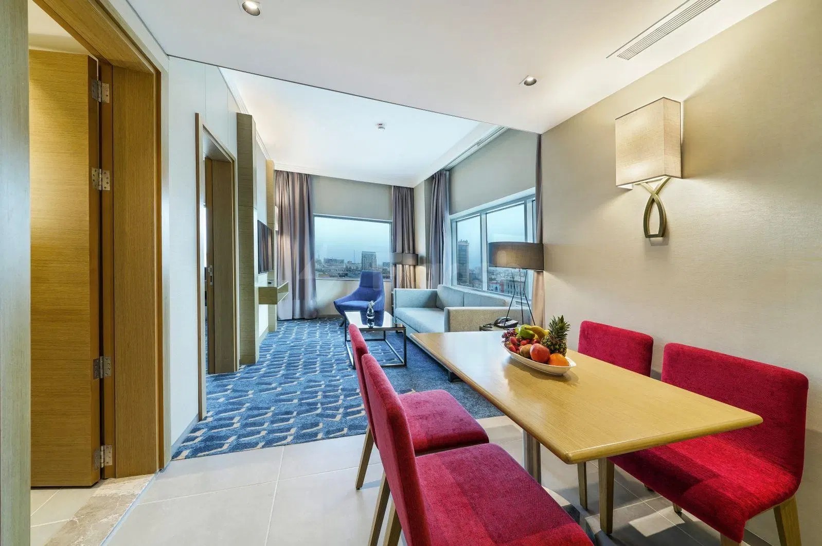 Living space at Dar Rayhaan by Rotana Al Khobar, featuring red chairs around a wooden dining table
