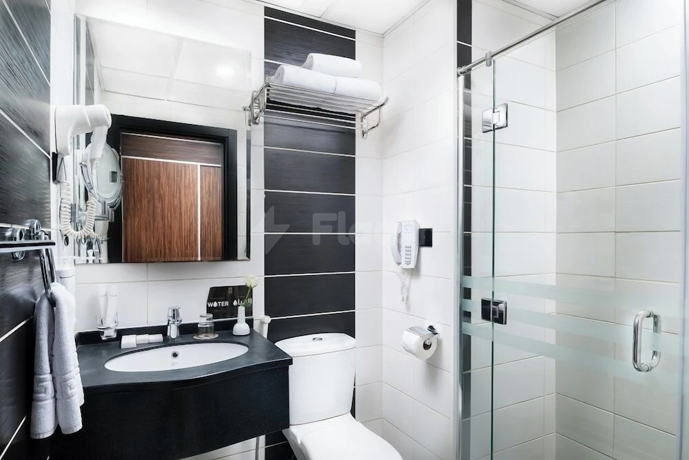 Bathroom at Elaf Bakkah, Mecca, featuring black wood accents and a glass shower enclosure
