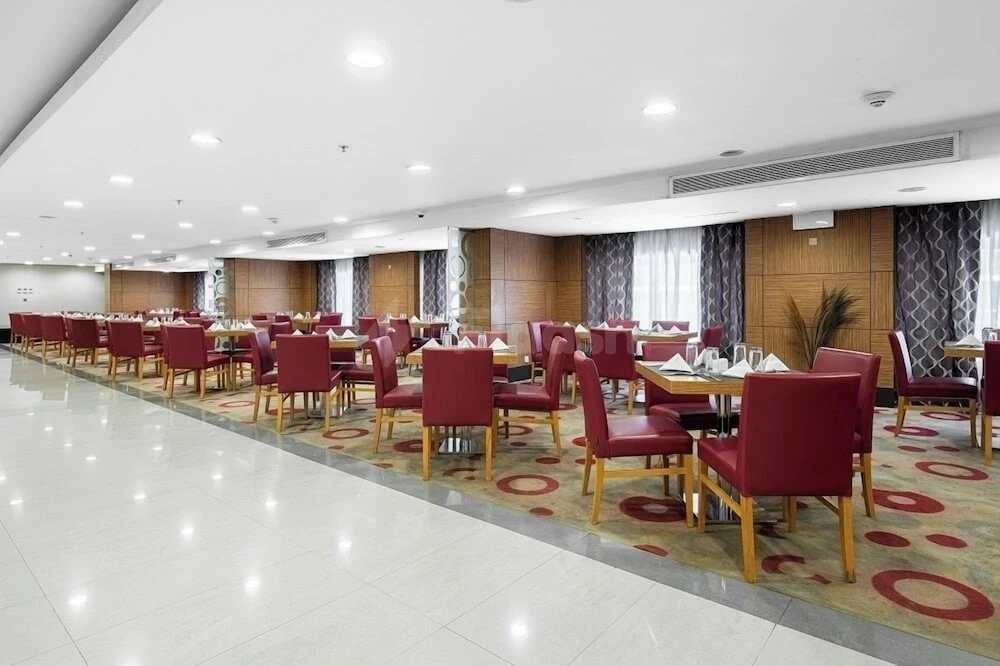 Dining hall at Elaf Bakkah, Mecca, with red upholstered chairs and patterned carpeting