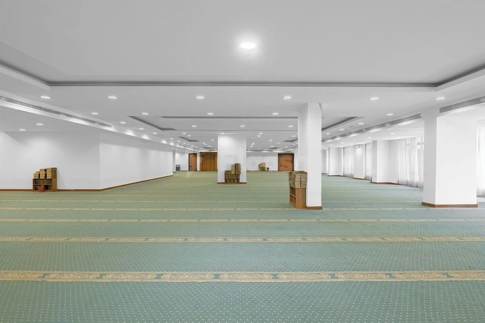 Prayer hall at Elaf Bakkah, Mecca, with green patterned carpet and white columns