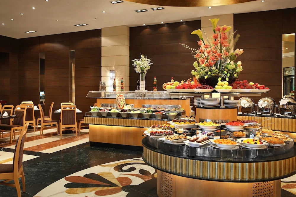 Buffet dining space at Al Marwa Rayhaan by Rotana - Makkah, featuring golden tiered displays and floral centerpieces