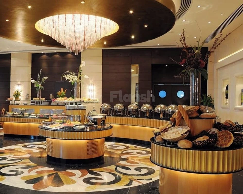 Buffet lounge at Al Marwa Rayhaan by Rotana - Makkah, featuring a grand crystal chandelier and ornate patterned flooring