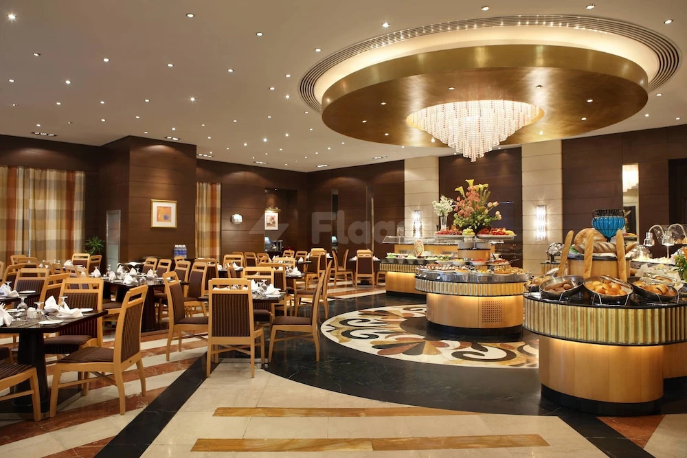 Dining room at Al Marwa Rayhaan by Rotana - Makkah, featuring circular chandeliers and polished marble floors with floral