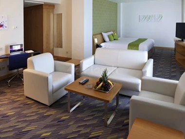 Lounge area at Novotel Dammam Business Park, Dammam, featuring white armchairs and a wooden coffee table with fruit