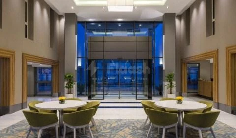 Lobby at Radisson Blu Residence, Dhahran, Al Khobar, with circular tables, green chairs and glass entrance