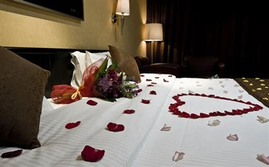Bedroom at Al Waha Palace Hotel, Riyadh, with rose petals arranged in heart shape on white linens