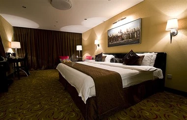 Guest room at Al Waha Palace Hotel, Riyadh, featuring plush bed with brown throw and wall art