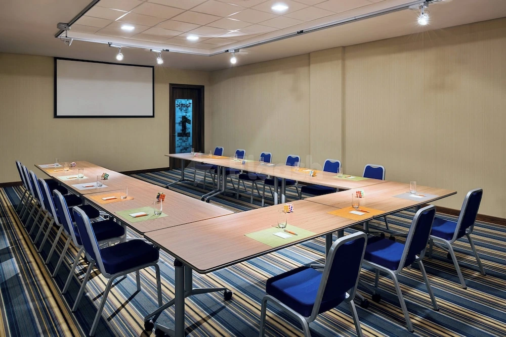Conference room at Aloft Dhahran, Al Khobar, with blue chairs and striped carpeting under track lighting ceiling lights
