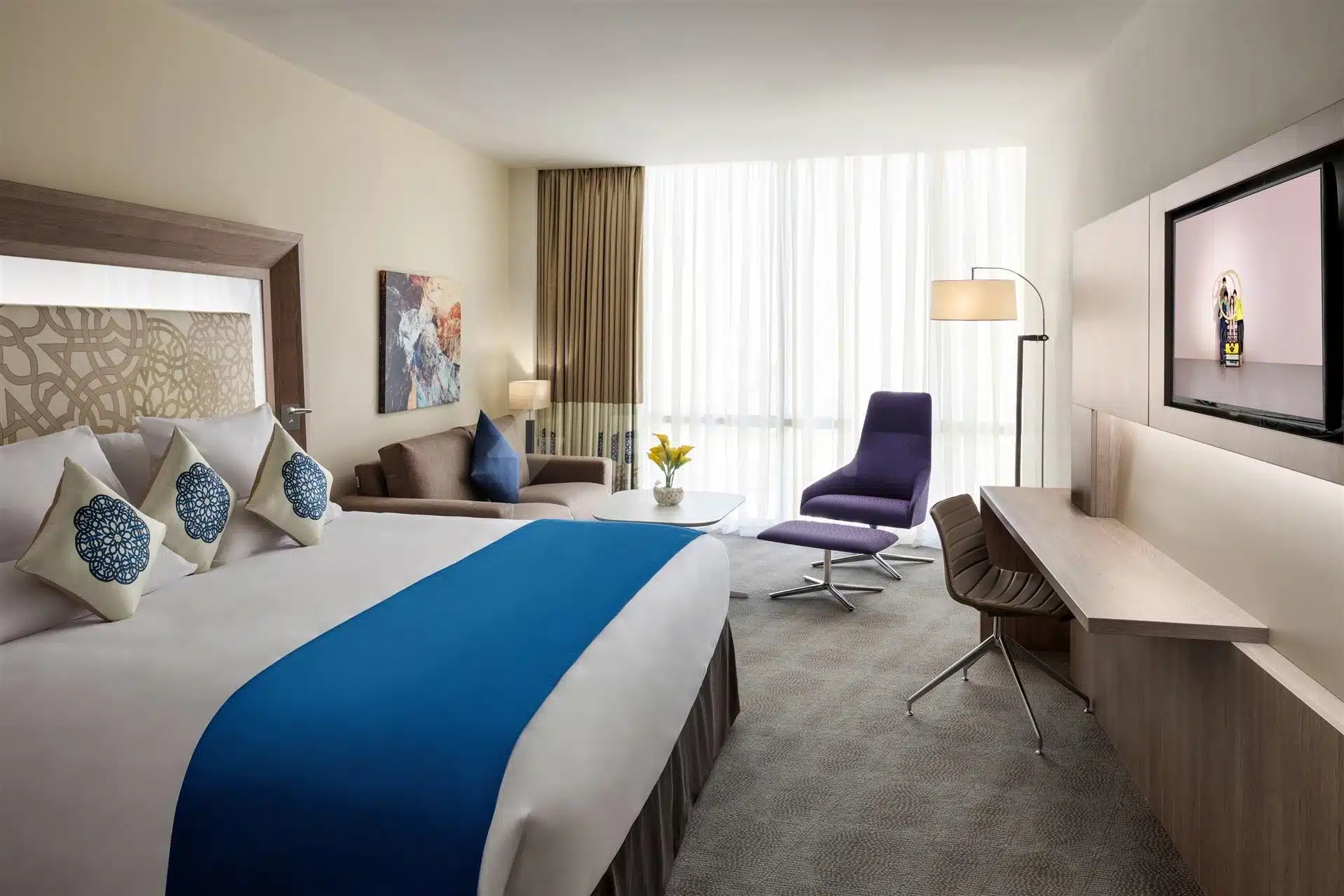 Guest room at Novotel Jeddah Tahlia Street, Jeddah, featuring blue accent pillows and a modern desk with purple