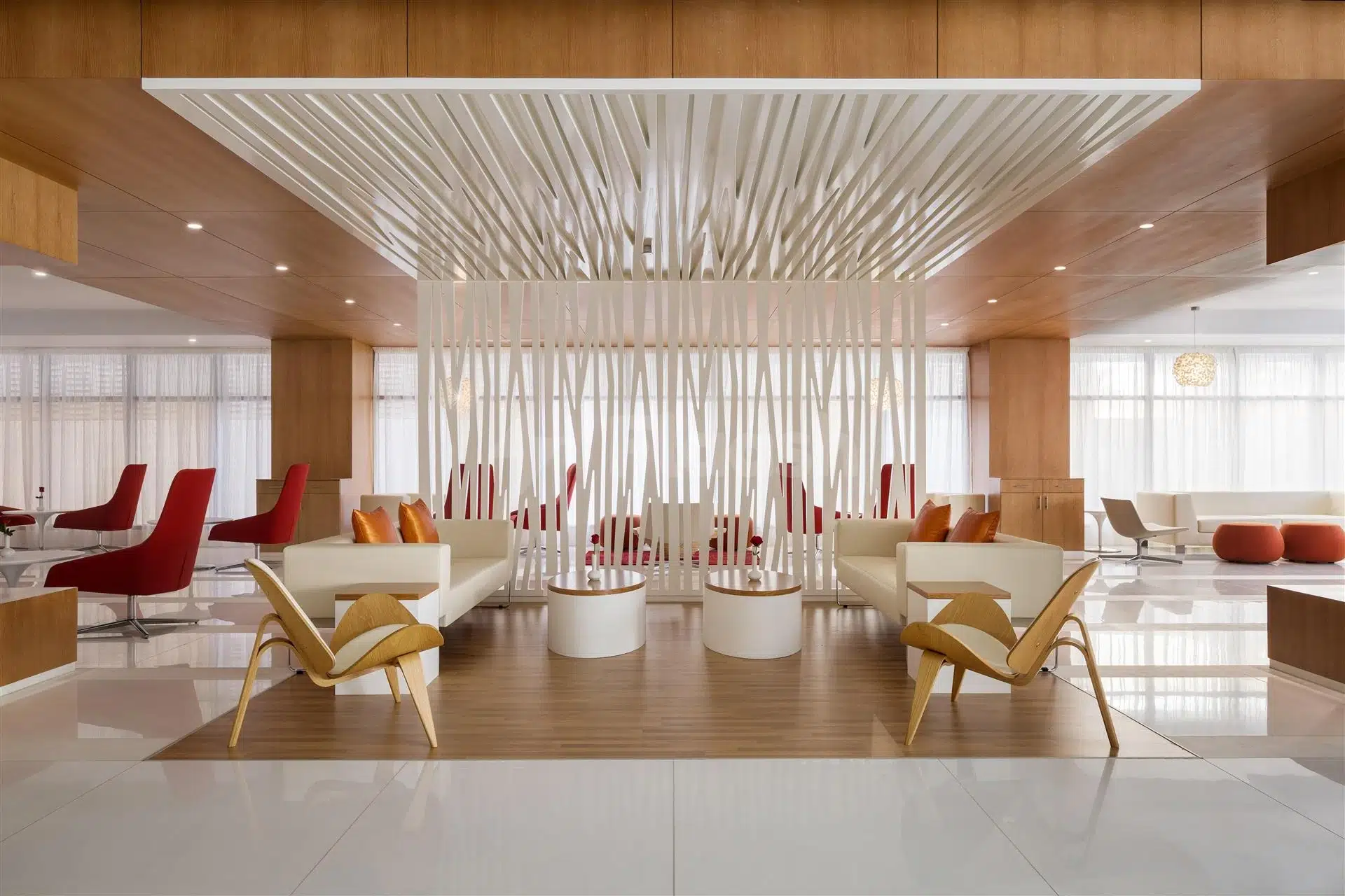 Lobby at interior at Novotel Jeddah Tahlia Street, Jeddah, featuring wooden slat ceiling and red accent chairs