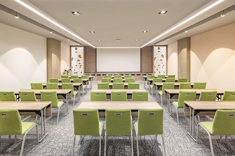Conference room at Park Inn Hotel by Radisson Riyadh, with green chairs and patterned carpeting under recessed ceiling
