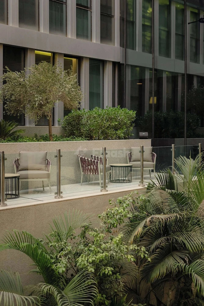 Outdoor terrace at Park Inn Hotel by Radisson Riyadh, featuring lounge chairs and lush greenery
