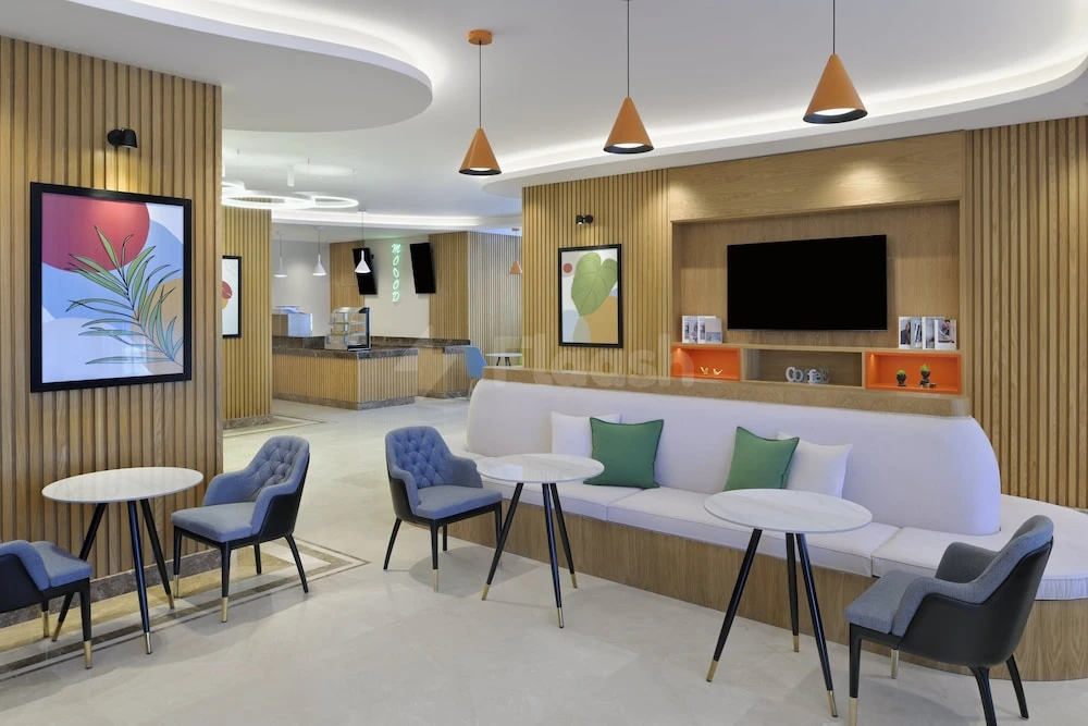 Lobby at Holiday Inn Jeddah Corniche, Jeddah, with wooden paneling and a framed tropical artwork