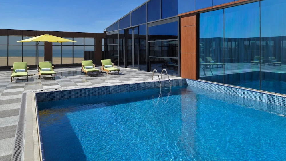 Outdoor pool at Holiday Inn Jeddah Corniche, Jeddah, with turquoise water and yellow umbrella facing sea view