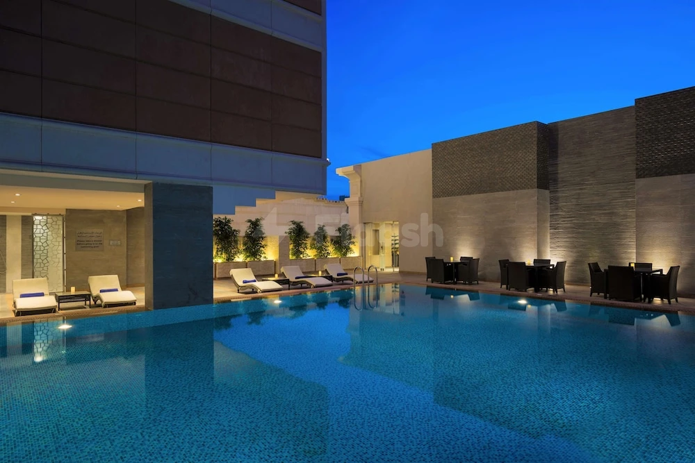 Outdoor pool at Radisson Blu Hotel Jeddah Al Salam, Jeddah, with lounge chairs and ambient lighting against twilight