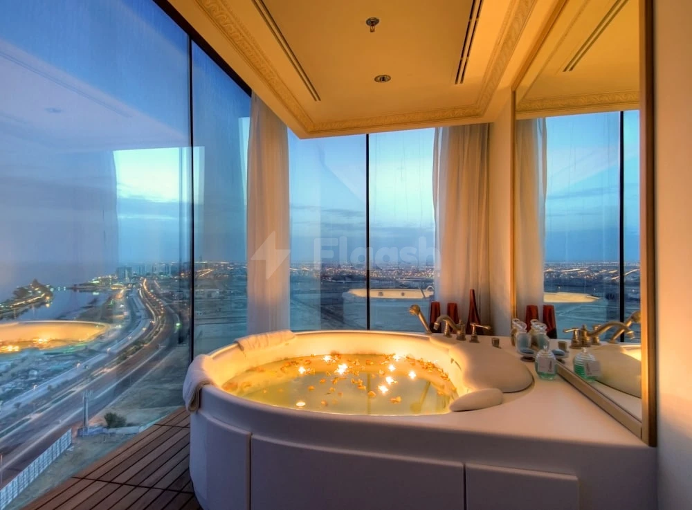 Luxury bathroom at Rosewood Jeddah, Jeddah, featuring a sunken tub with floating candles and panoramic city views
