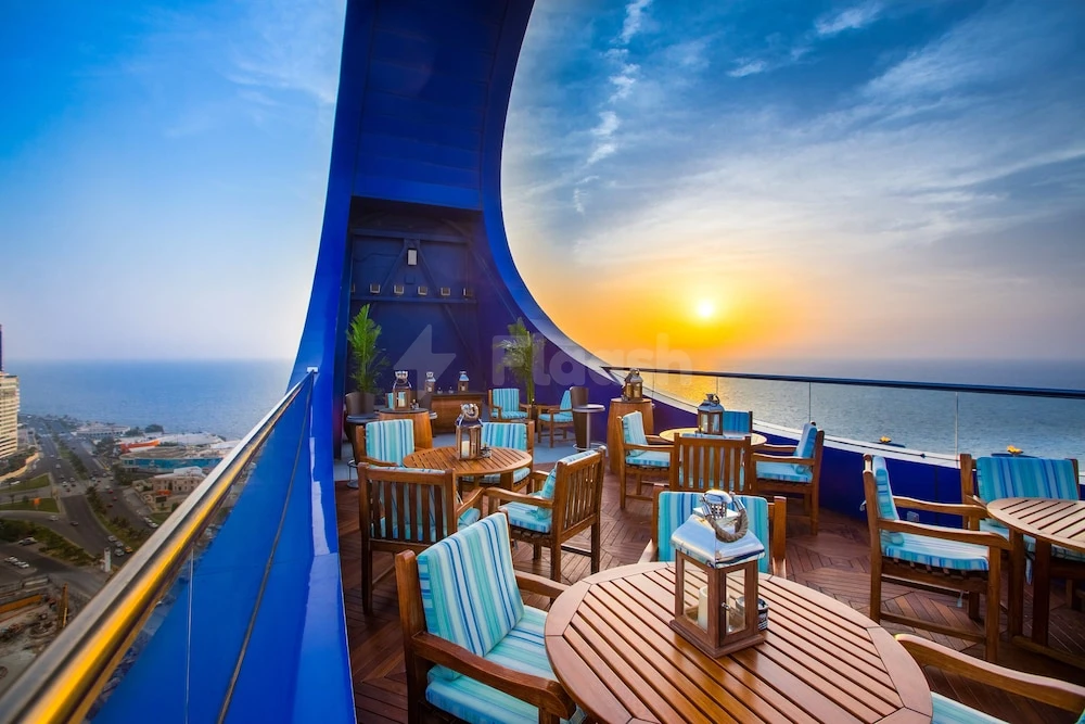 Rooftop terrace at Rosewood Jeddah, Jeddah, with blue curved walls and sunset over sea