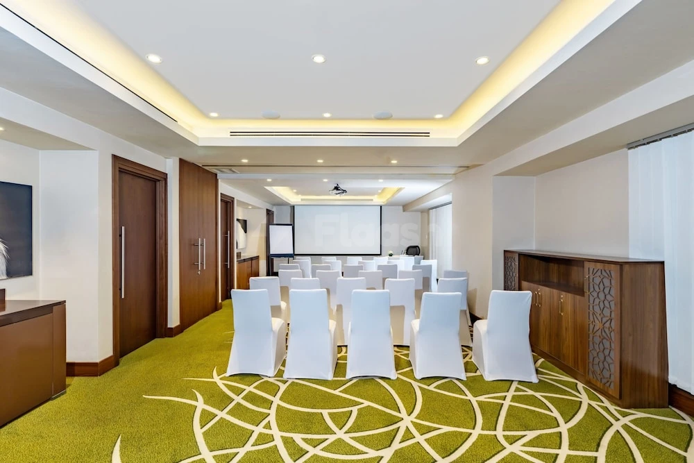 Conference room at Courtyard by Marriott Riyadh Olaya, Riyadh, with green patterned carpet and white chairs arranged facing