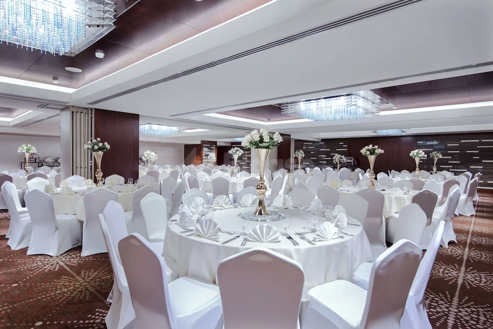 Banquet hall at Rosh Rayhaan By Rotana, Riyadh, with crystal chandeliers and white linen-covered tables