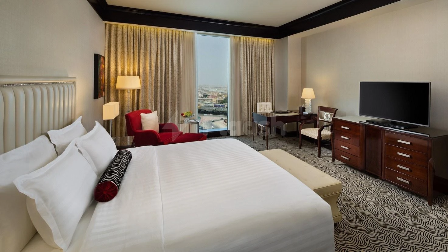 Guest room at Kempinski Al Othman Hotel, Al Khobar, featuring plush white bedding and city-view windowogy from large