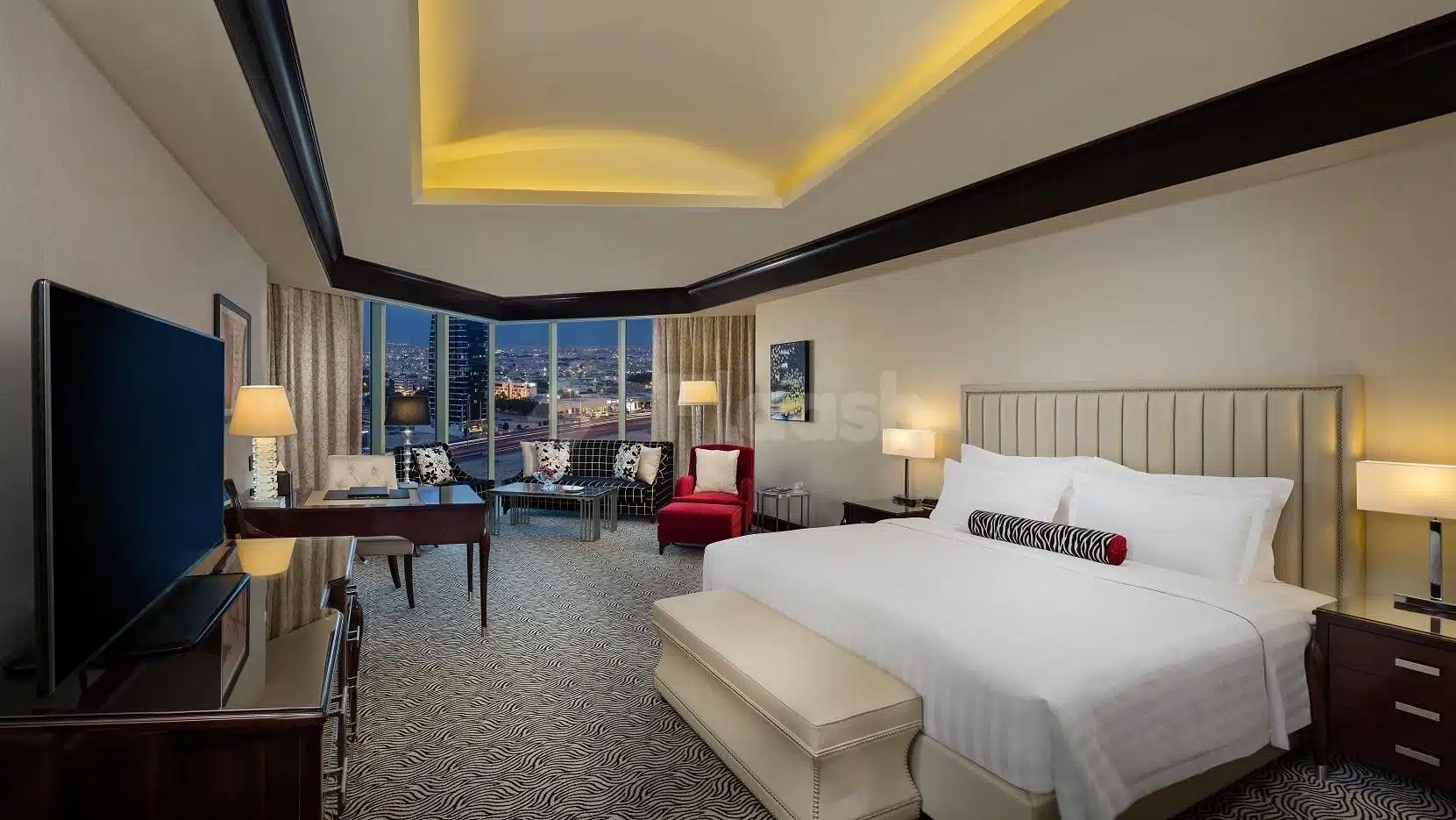 Luxury suite at Kempinski Al Othman Hotel, Al Khobar, featuring city lights view through large windows and modern