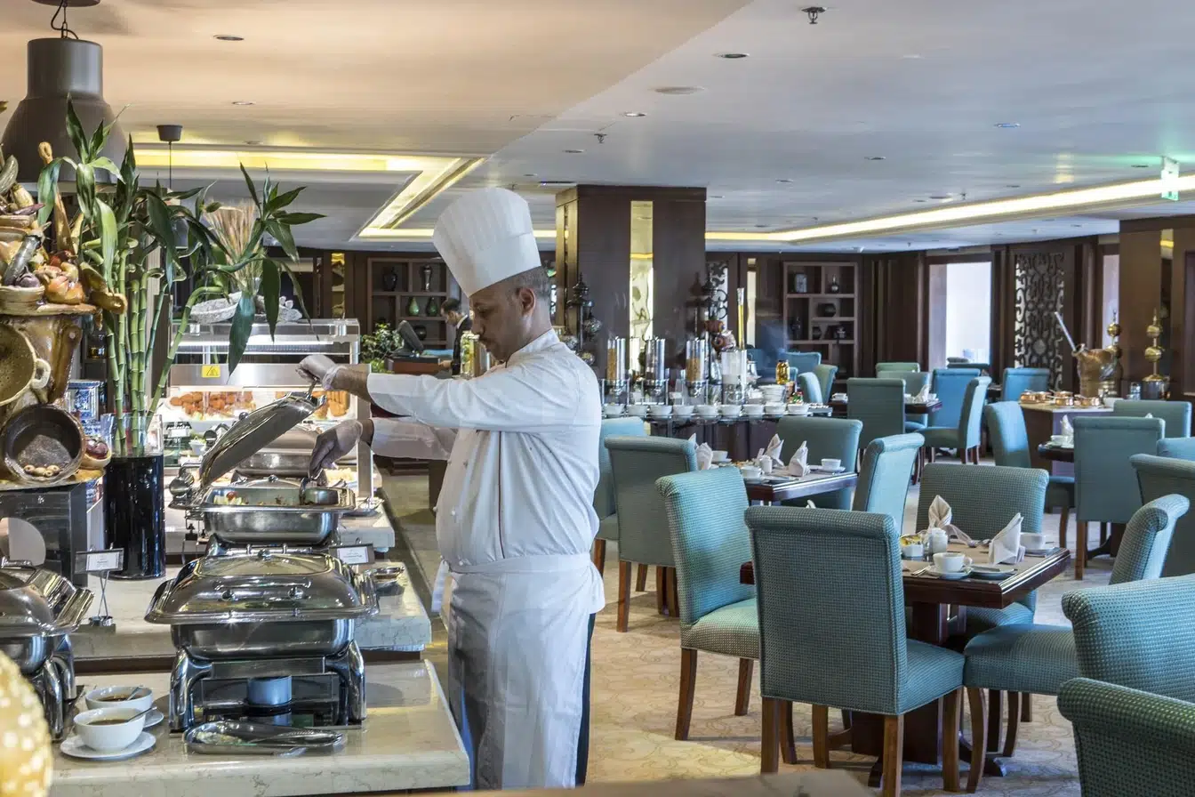 Dining area at Crowne Plaza Riyadh Al Waha, Riyad, with chef serving food from a buffet station