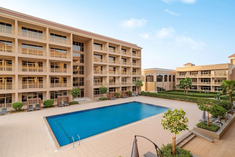 Outdoor pool courtyard at Radisson Hotel Riyadh Airport, Riyadh, featuring rectangular blue pool bordered by lounge chairs