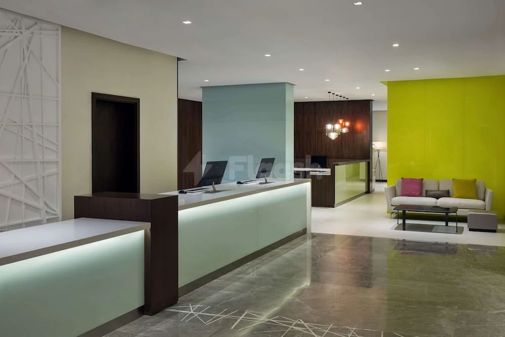 Lobby at Hyatt House Jeddah Sari Street, Jeddah, with illuminated reception desk and vibrant lime green accent wall