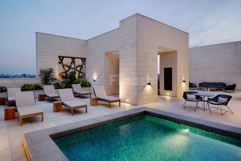 Rooftop terrace at Hyatt House Jeddah Sari Street, Jeddah, featuring a glowing pool and lounge chairs under twilight