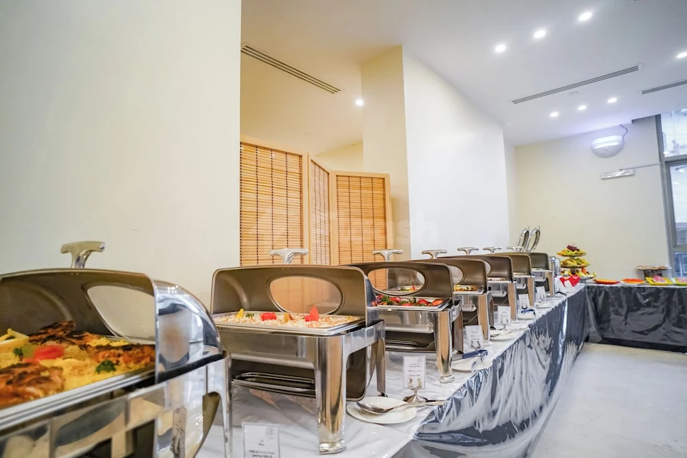 Buffet setup at Emaar Elite Makkah Hotel, Makkah, featuring stainless steel chafing dishes lined on a table covered