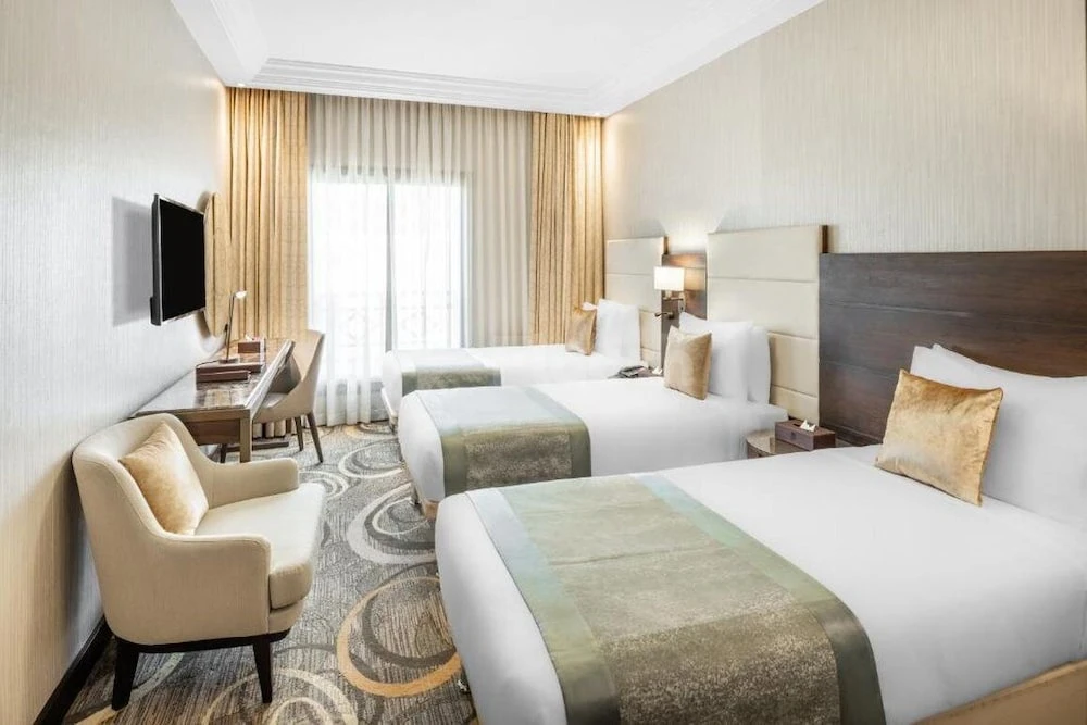 Guest room at Millennium Makkah Al Naseem, Mecca, with three beds and patterned carpeting