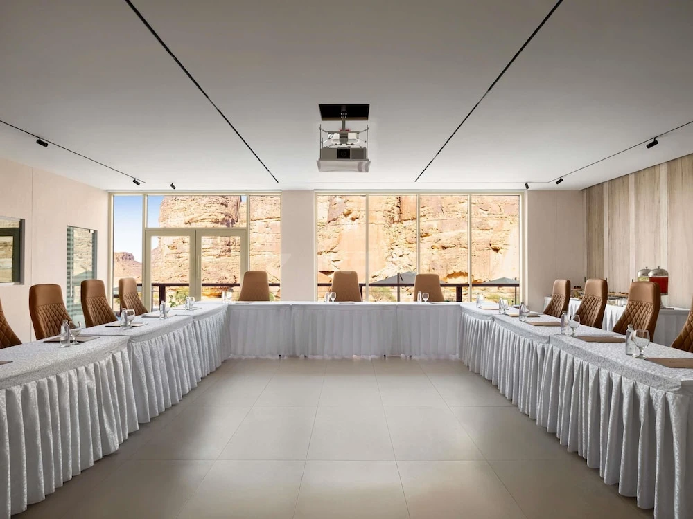 Conference room at Shaden Resort, AlUla, with U-shaped tables and desert rock views through floor-to-ceiling windows