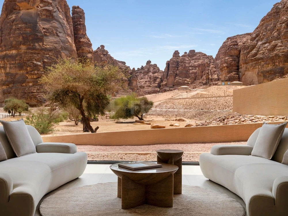 Lounge area at Shaden Resort, AlUla, featuring white sofas and stone tables facing rugged desert cliffs