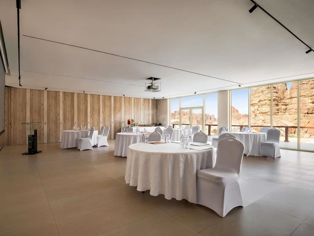 White draped tables at 325 at Shaden Resort,, AlUla, with desert rock formations visible through large windows