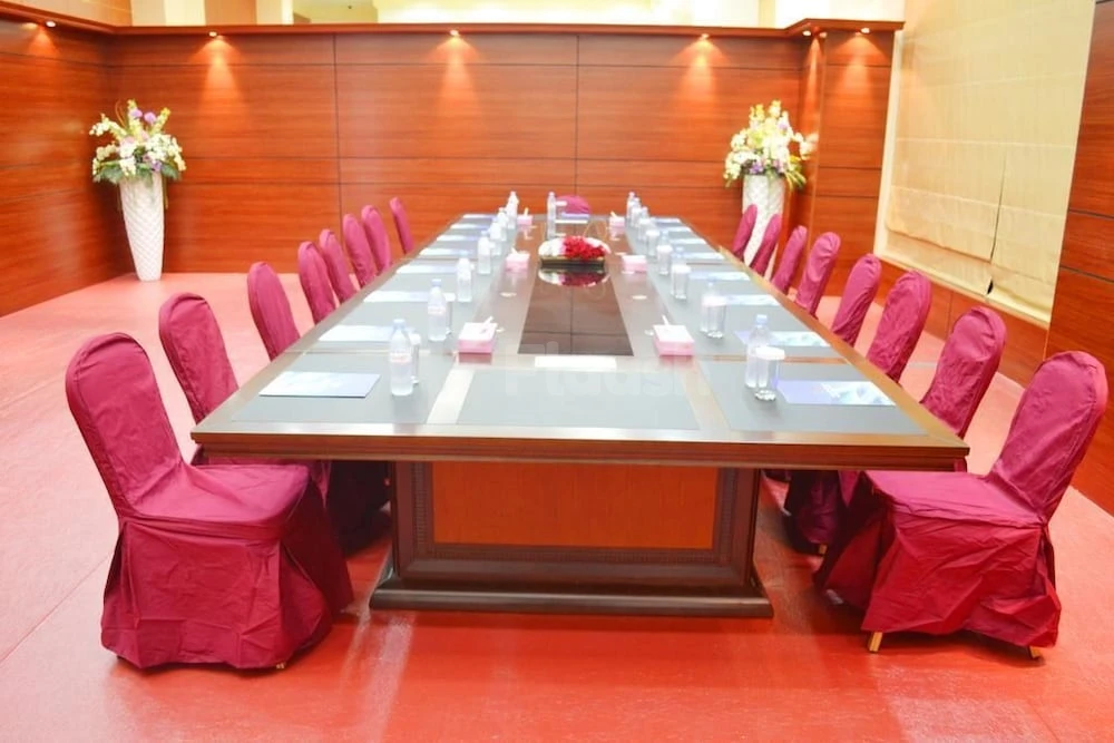 Boardroom at Al Massa Hotel, Mecca, with burgundy chair covers and floral arrangements on wooden panel walls
