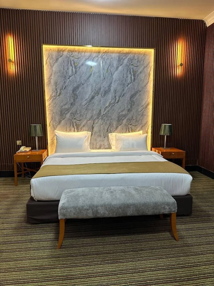 Guest room at Al Massa Hotel, Mecca, featuring marble headboard with warm backlighting and wooden bedside tables