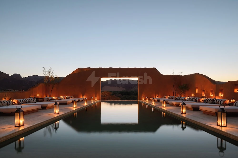 Infinity pool at Dar Tantora The House Hotel, AlUla, framed by desert rock arch and lanterns