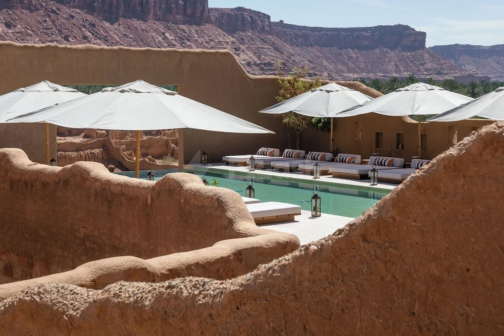 Pool terrace at Dar Tantora The House Hotel, AlUla, framed by terracotta walls and desert cliffs