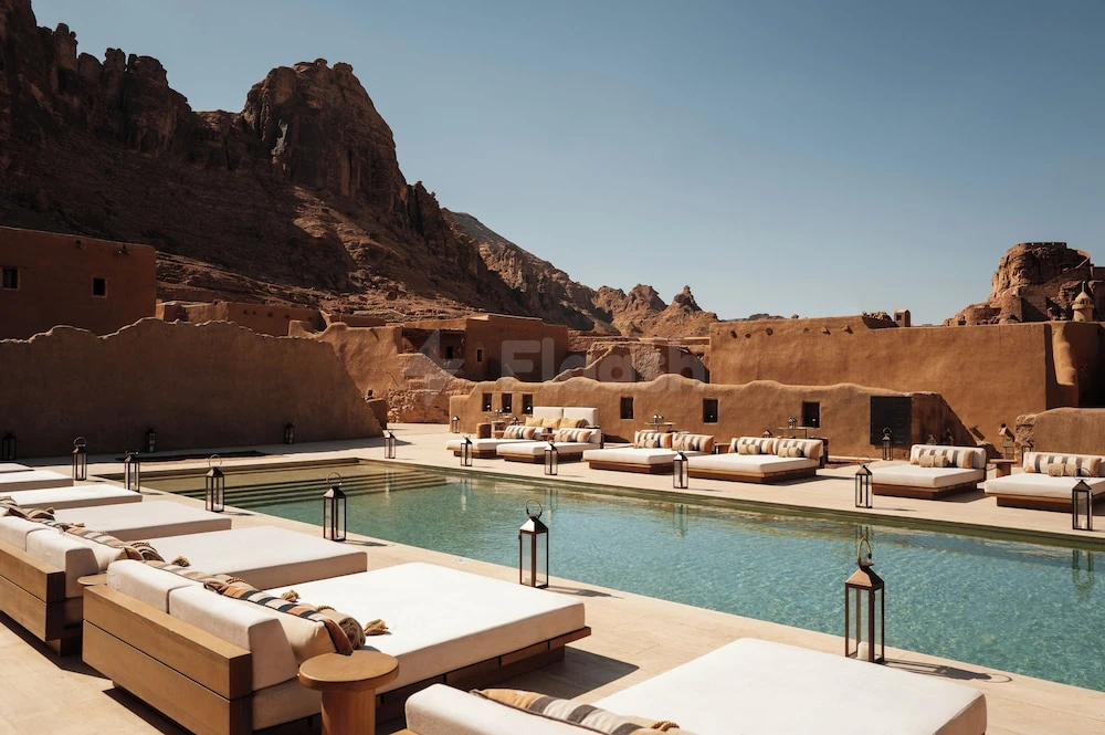 Poolside lounge at Dar Tantora The House Hotel, AlUla, with terracotta walls and lanterns against rugged mountains