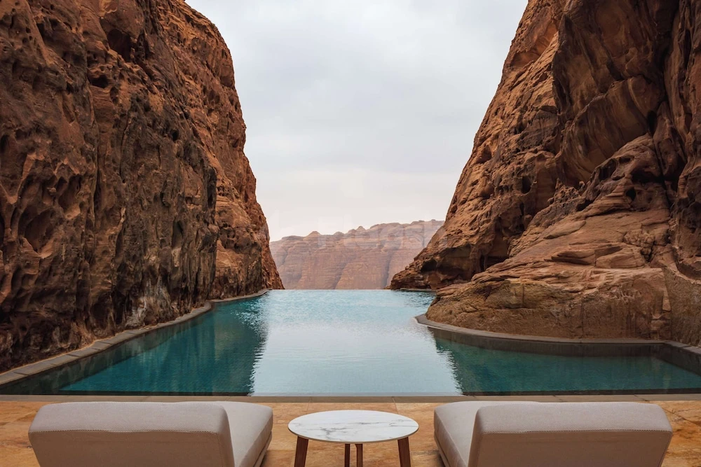 Infinity pool at Banyan Tree AlUla, AlUla, nestled between towering red rock cliffs with calm turquoise water reflecting