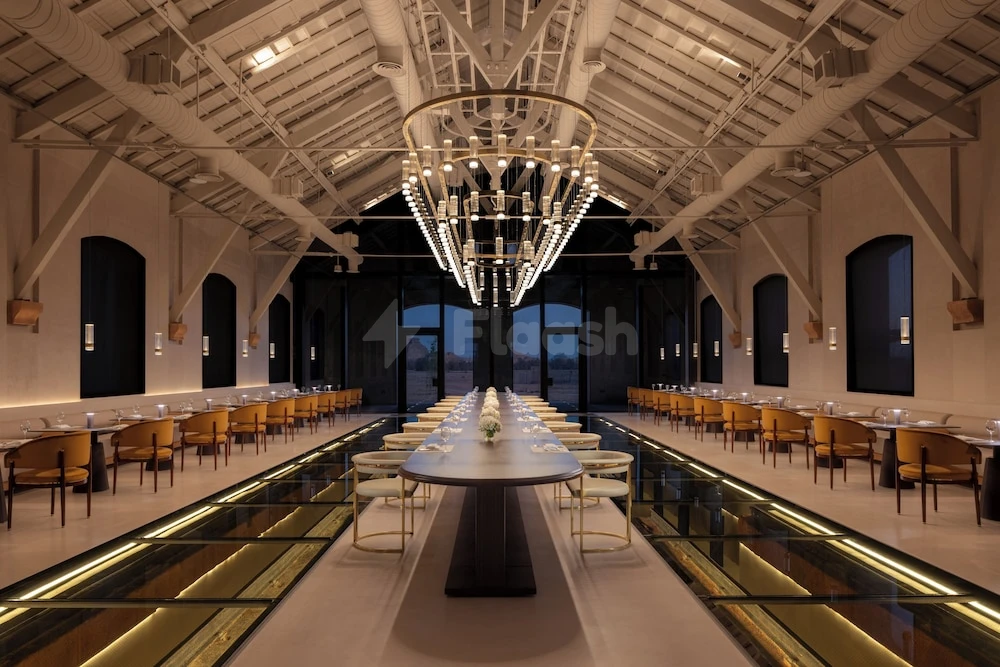 Dining hall at The Chedi Hegra, AlUla, featuring a grand chandelier and glass-floored walkway with arched doorways